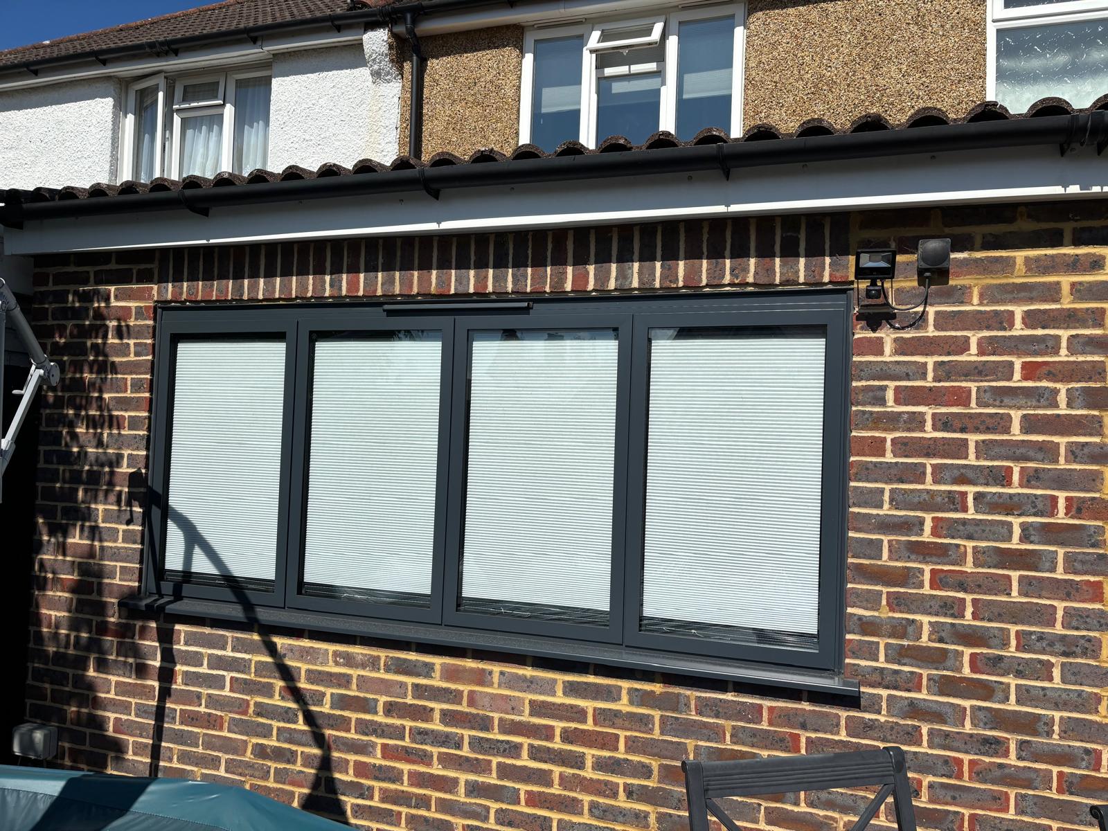 Finished four-panel grey aluminium window unit set into new brickwork