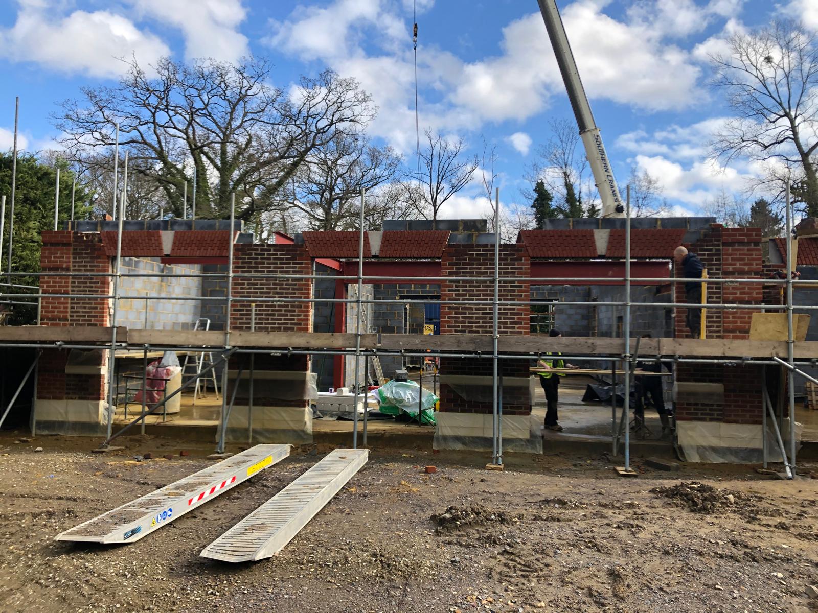 A separate brick outbuilding on the same site under construction, with matching brick detailing