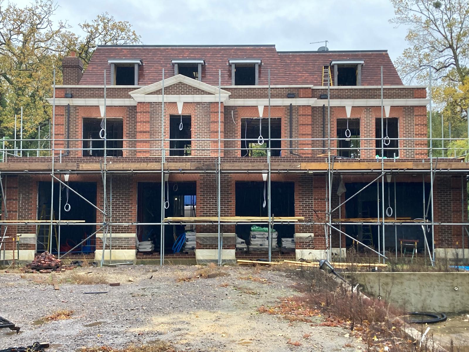 Rear elevation of the same new-build house, showing dentil brick coursing and window openings under scaffold