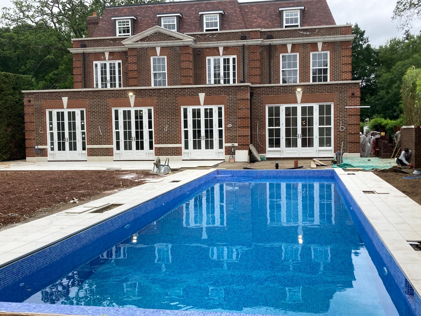 Finished rear elevation with white French doors fitted and pool being tiled